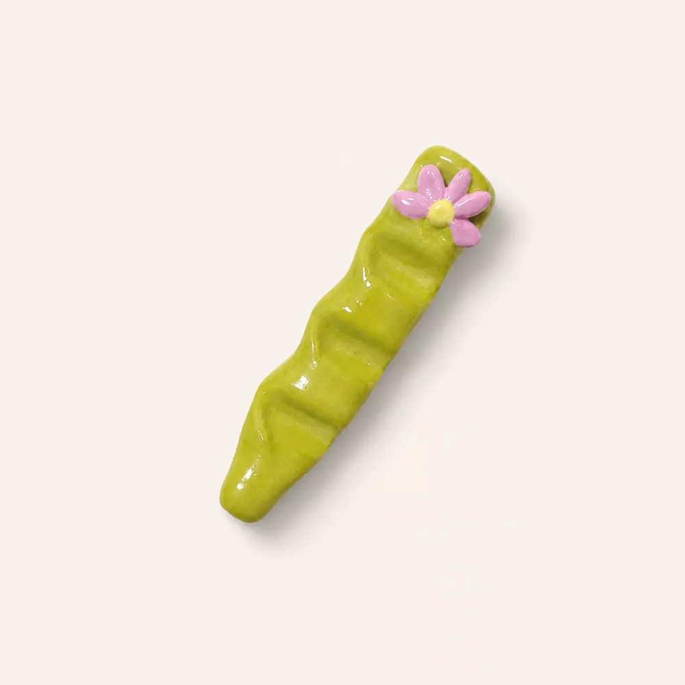 Handmade green clay decor with a pink flower accent.