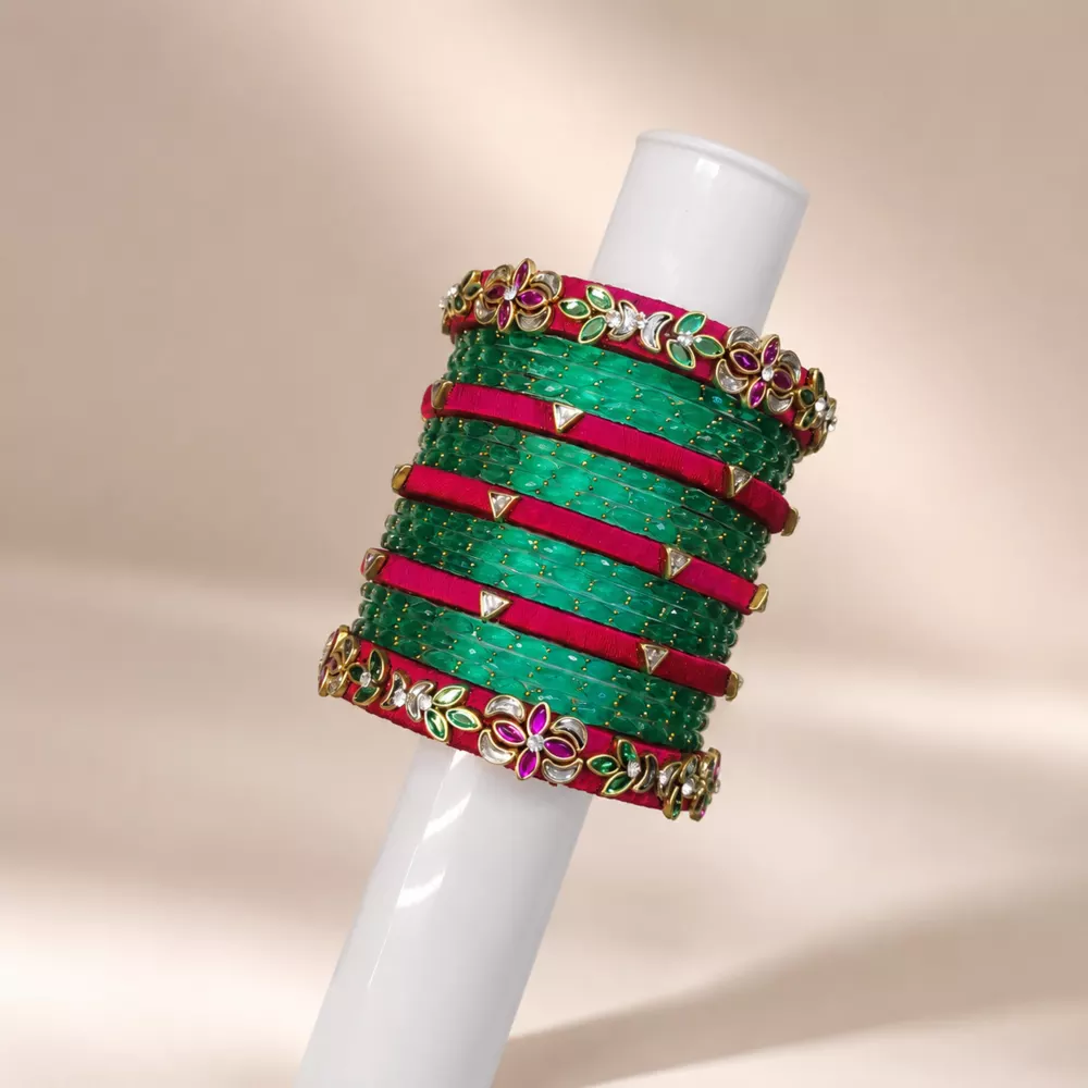 Green and pink silk thread bangle set displayed on a stand.
