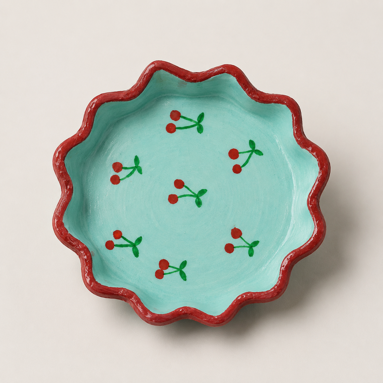 Aqua scallop trinket tray with cherry artwork and a red border.